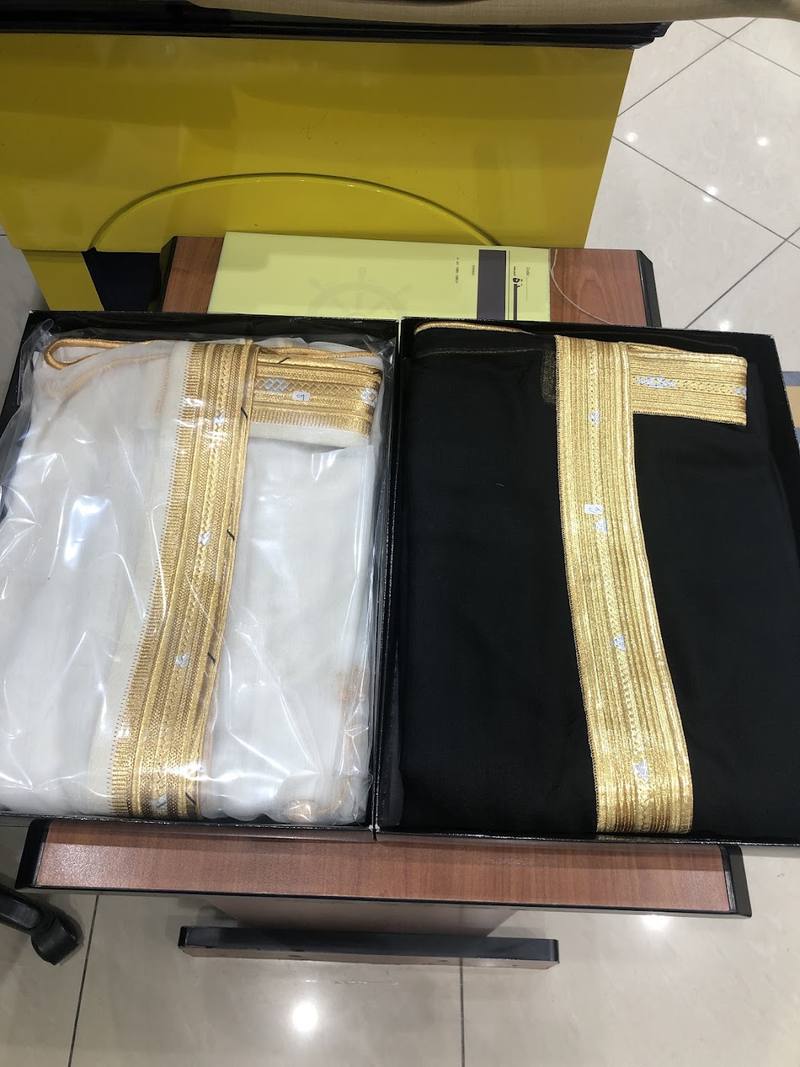 Black and cream bishts with gold trim, folded in their boxes