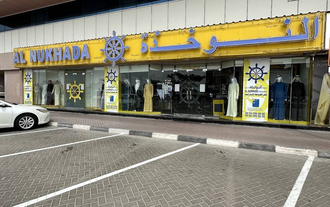 Al Nukhada by day: the yellow fascia with the ship's wheel, and parking in front